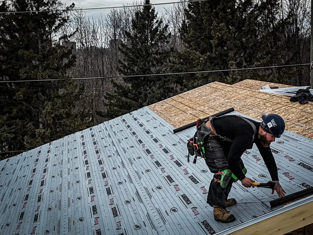 A construction worker installing a new roof on a residential home addition, showcasing professional building techniques and materials.