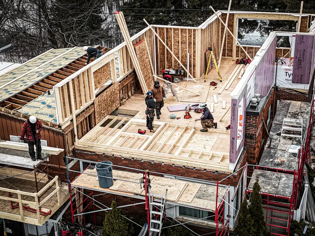 Construction workers framing a house addition, showcasing the structural integrity and craftsmanship involved in residential projects.